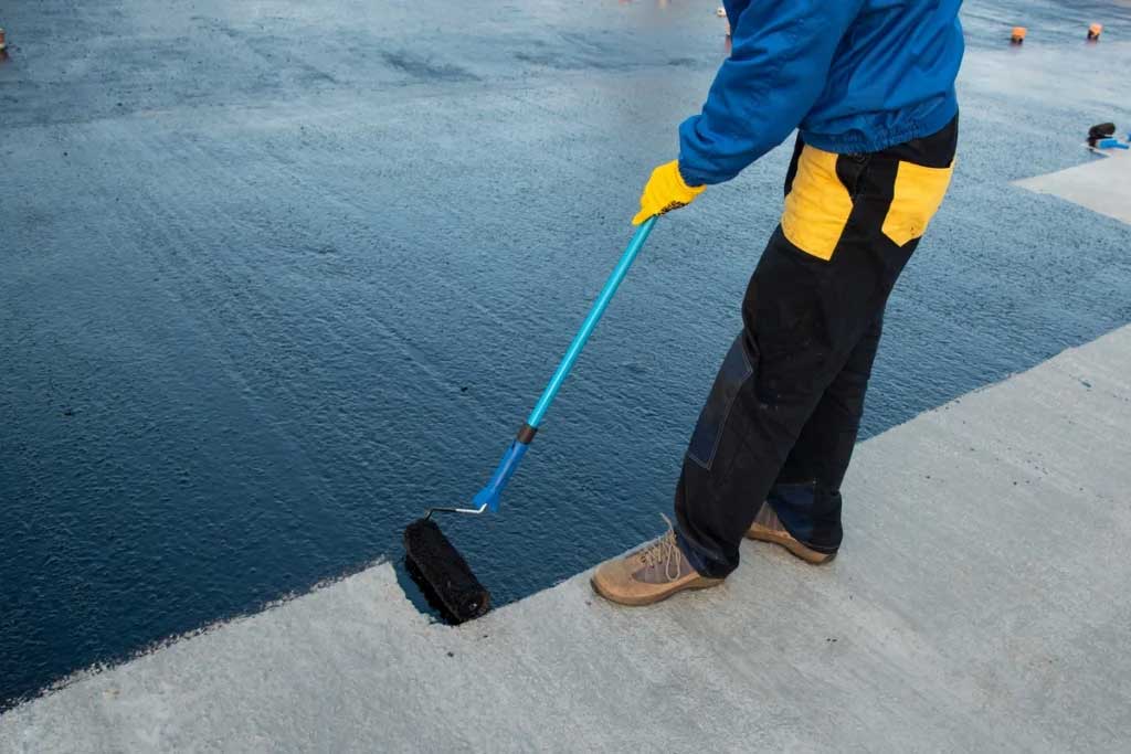 a person doing black roof coating