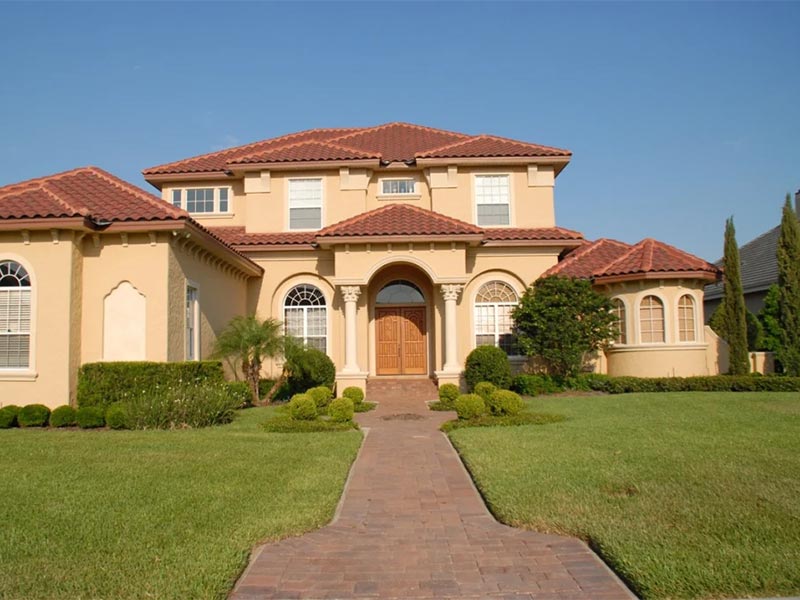 Mediterranean-style house with tiled roof and front lawn.