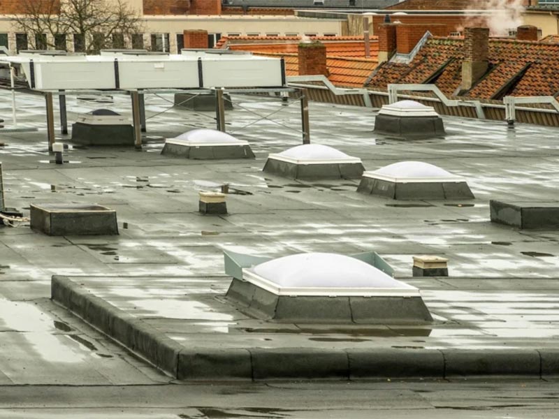 Flat commercial roof with multiple ventilation domes.