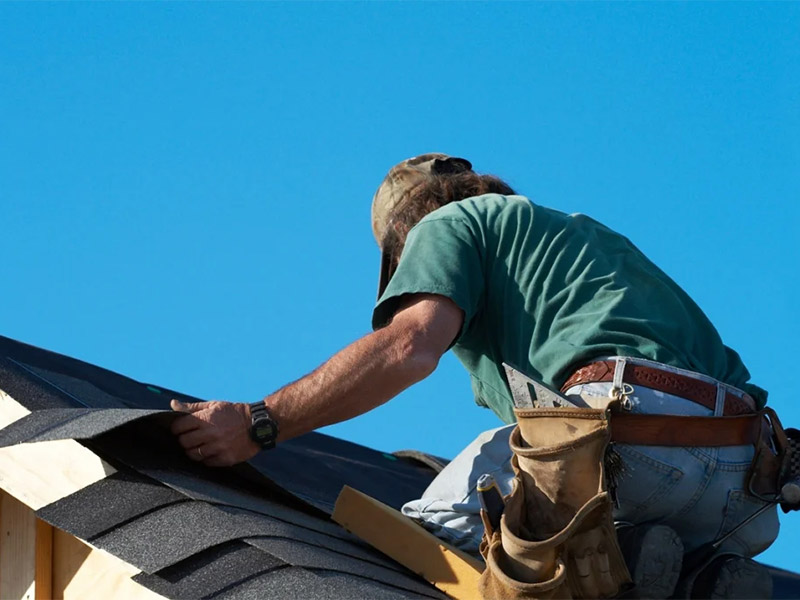 Contractor installing asphalt shingles on a roof