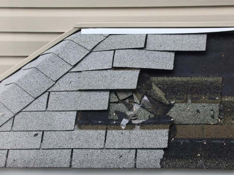 Close-up of damaged asphalt roof shingles.