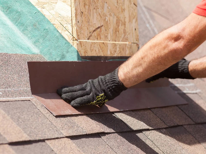 A worker leveling the asphalt roof.