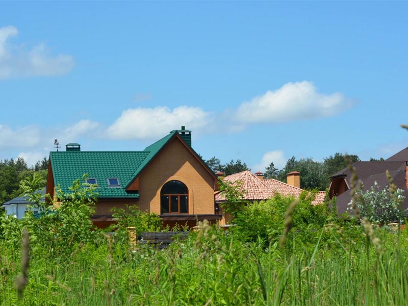 House with green metal roof in a rural setting.
