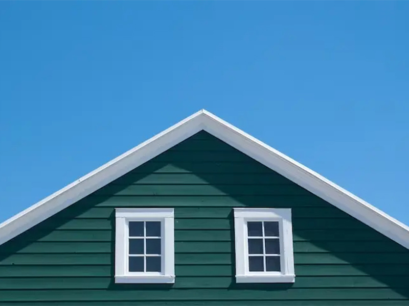 Green house siding with white-trimmed windows.
