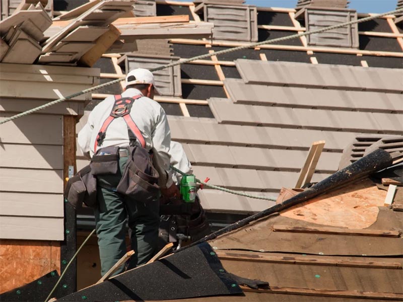 Person repairing a damaged roof with tools.