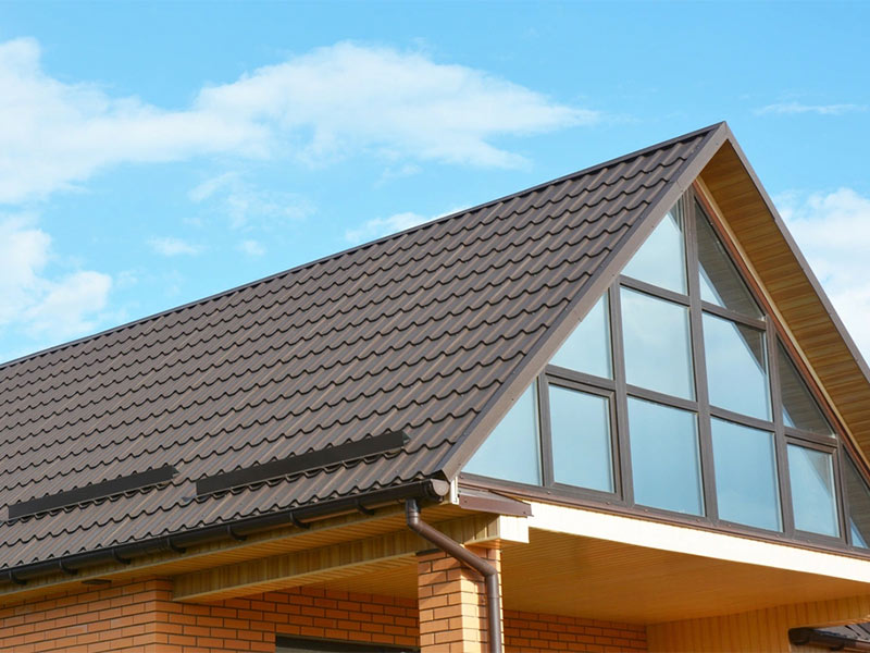 Brick house with dark metal roof and large windows.