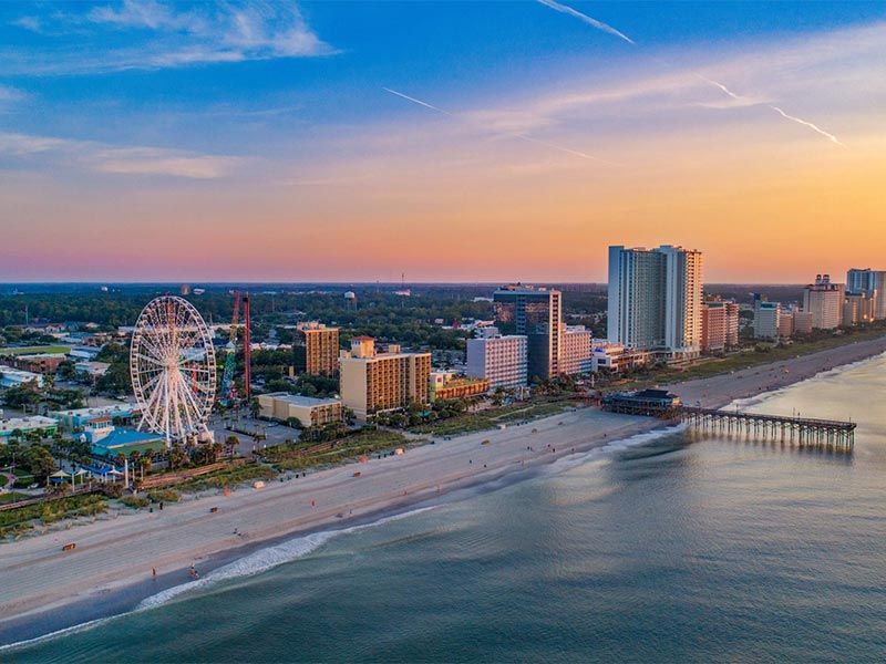 Aerial view of a beachfront city skyline at sunset.