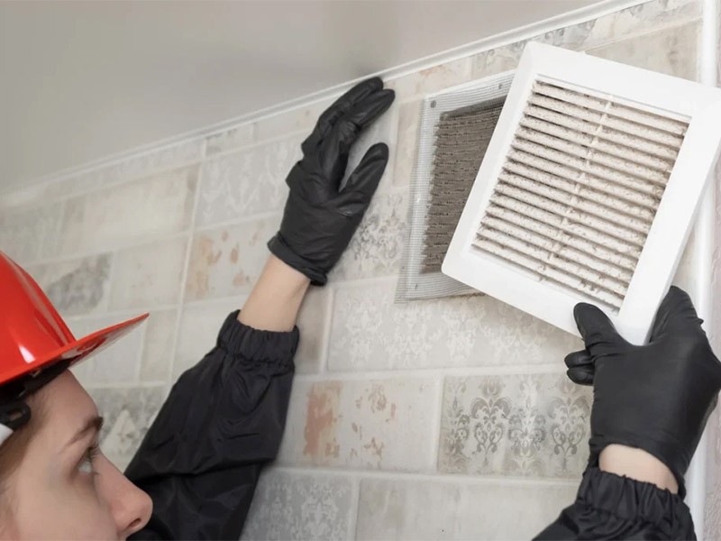 Person installing a wall ventilation vent.
