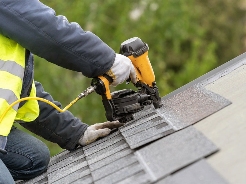 Professional roofer repairing asphalt shingles