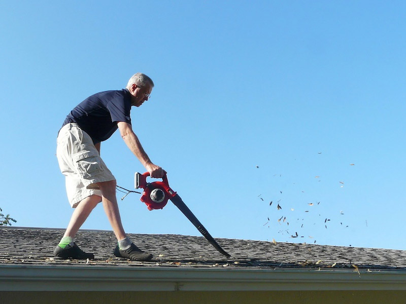 Cleaning debris from roof gutters.