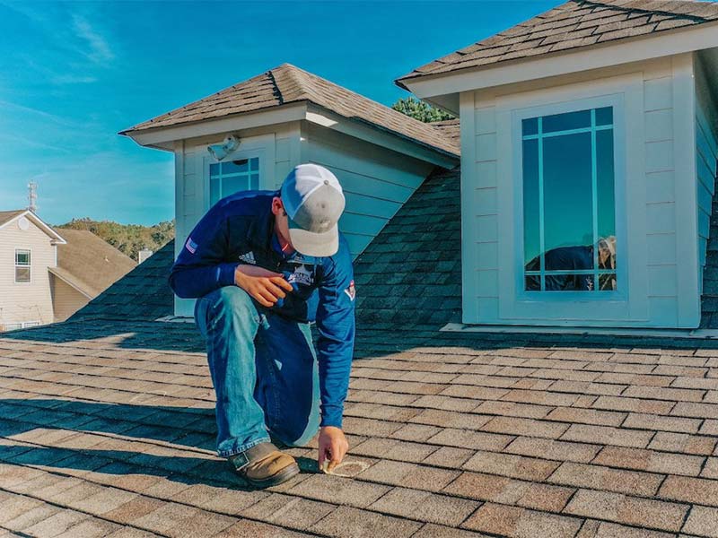 Roofer marking roof shingles for repair