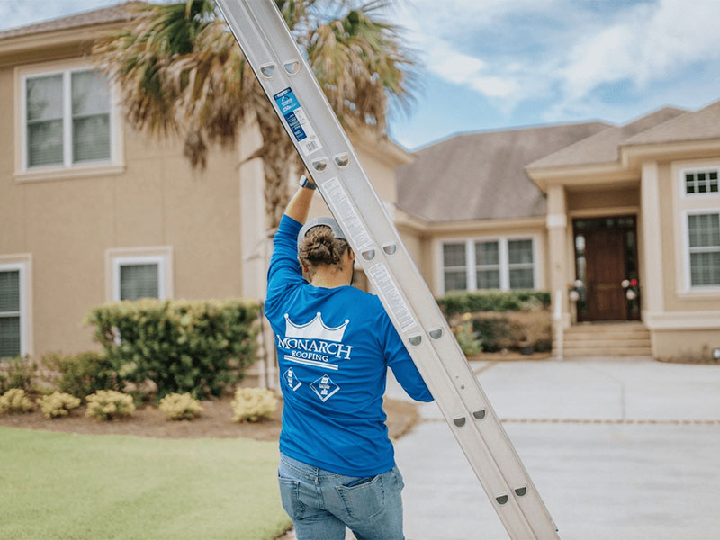 Roofing worker carrying ladder for inspection