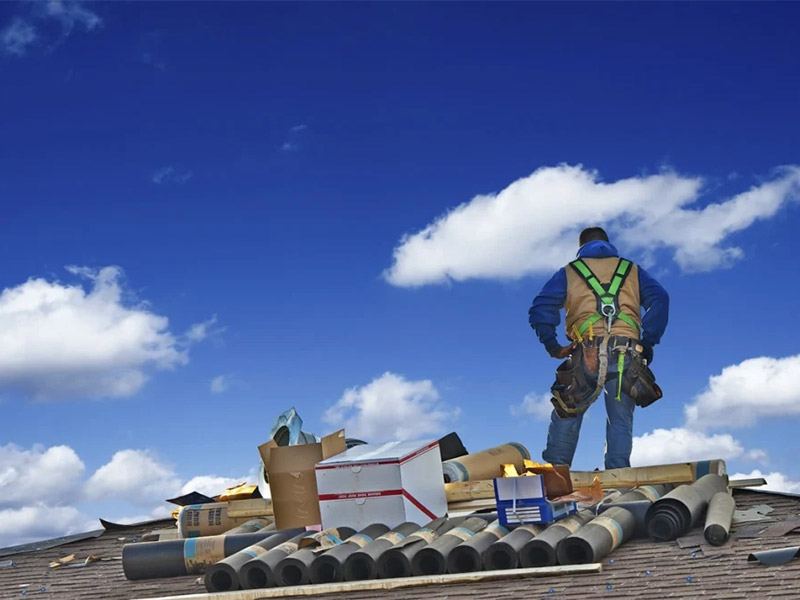 Roofing contractor standing on a roof with materials.