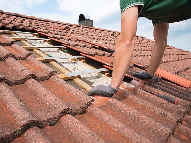 Technician repairing a leaking tile roof