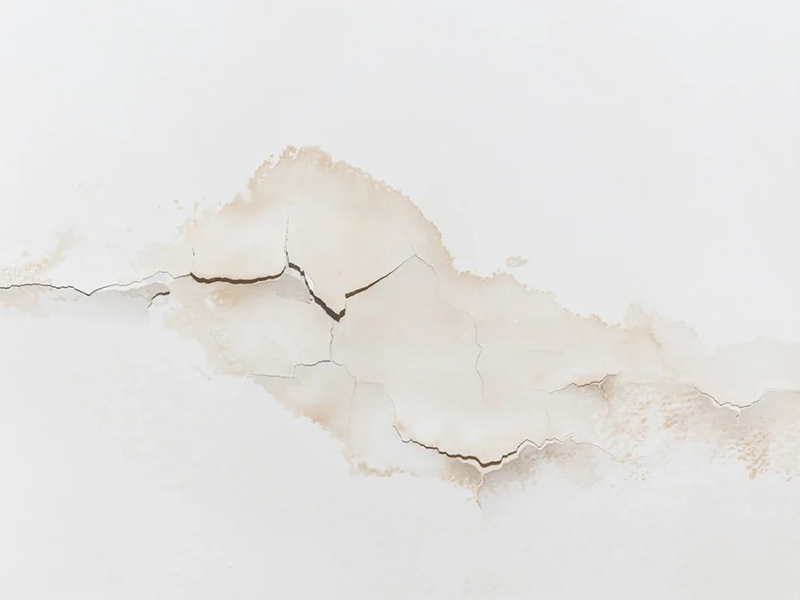 Water stains and cracks on an indoor ceiling.