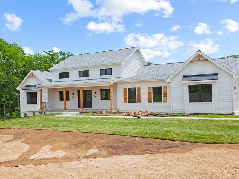 White house with a gray shingle roof and porch.